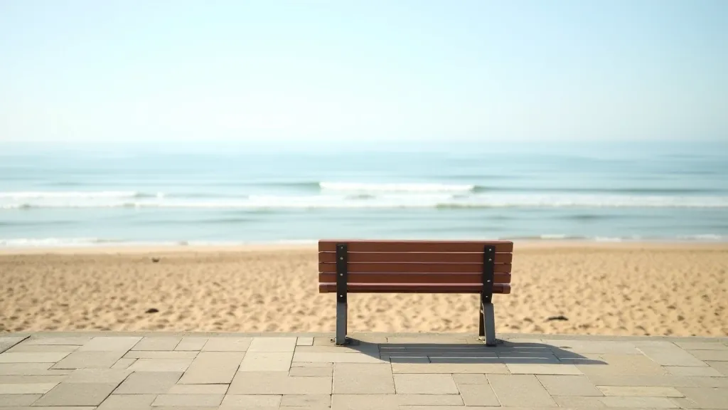 Wooden bench on coastal promenade overlooking sandy beach and ocean, bright sunny day, inviting seating area